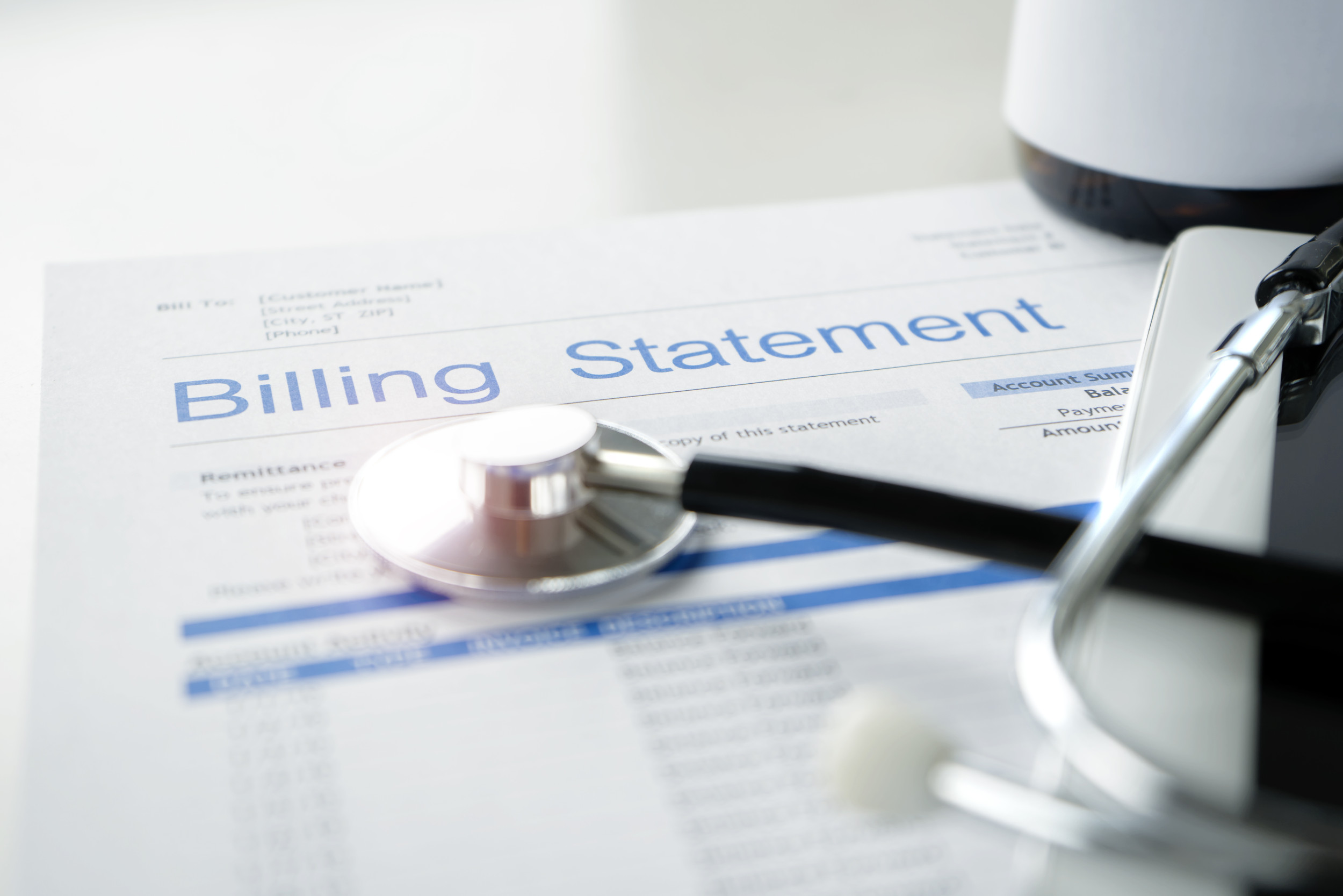 Health care billing statement with stethoscope, bottle of medicine for doctor's work in medical center stone background. (Getty)